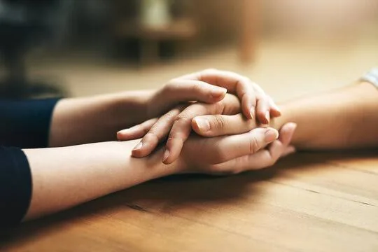 Two people holding hands in a gesture of supportive connection